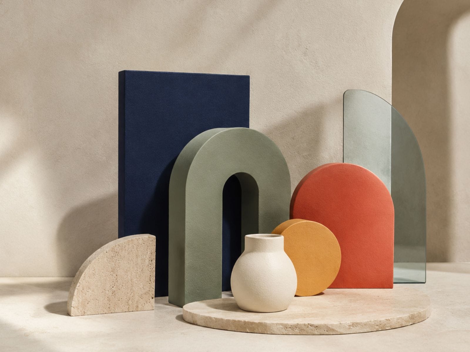 Abstract still life of navy, sage, coral, ochre, cream and translucent glass geometric forms in a softly lit studio.