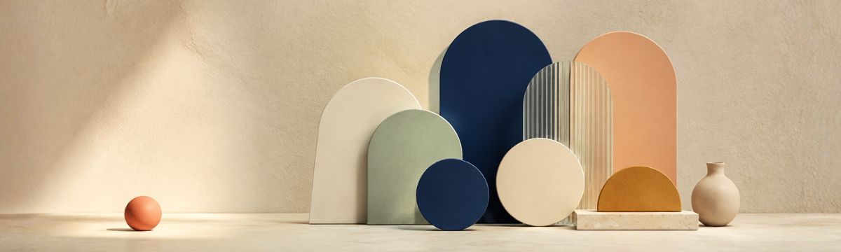 A single warm coral object develops into a coordinated palette of cream, sage, navy, peach and ochre geometric forms.