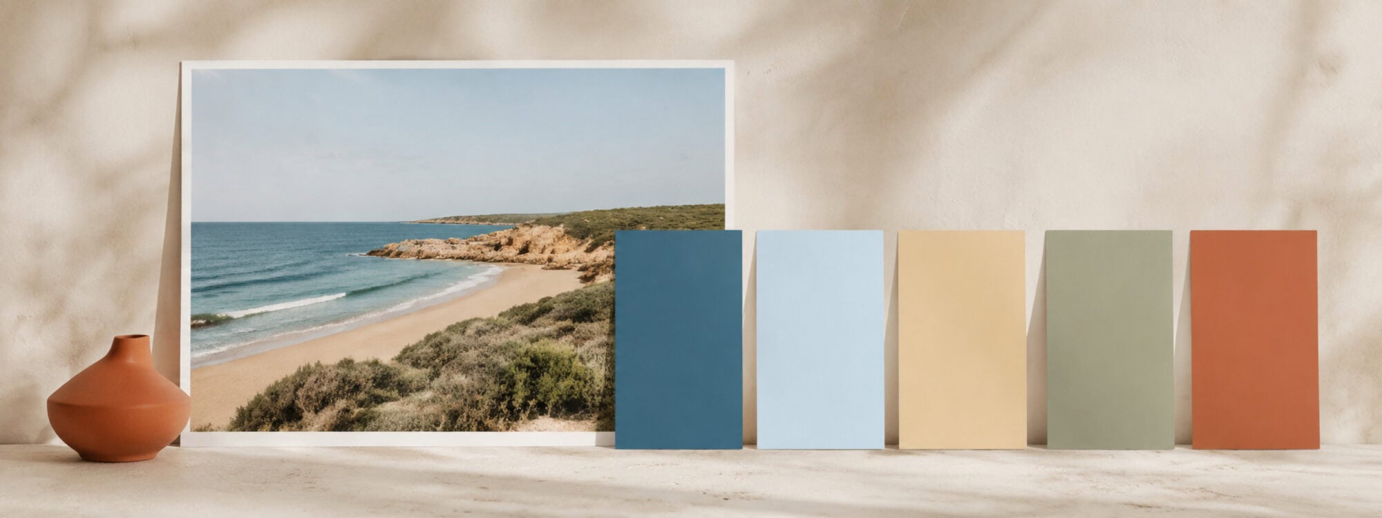 Coastal photograph beside five coordinated color swatches in deep blue, pale blue, sand, sage green and terracotta.